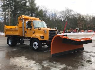 Photo of truck with plow attachment on front parked on wet, icy parking lot