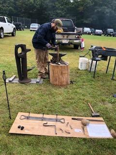 A blacksmith works at an anvil at Field Day
