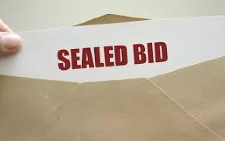open envelope with paper that has "sealed bid" written in red ink