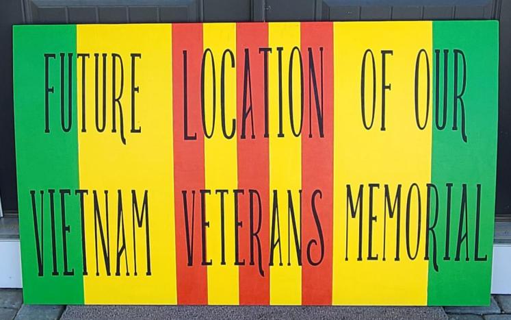 text future location of our vietnam veterans' memorial on painted wood sign